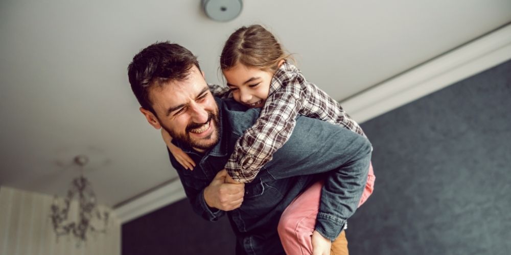 Dad carrying his daughter on his back.