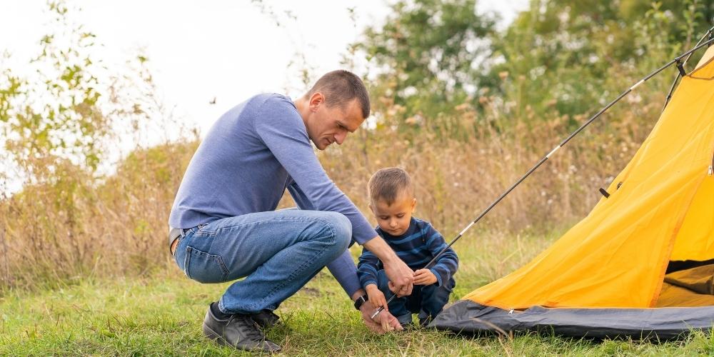 Dad setting up a tent with his son.