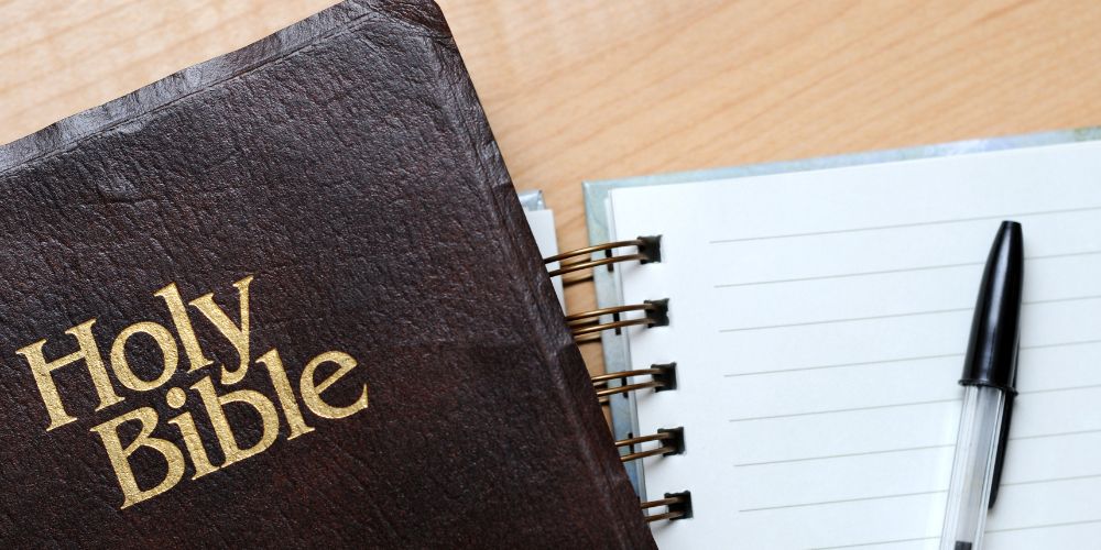A Bible is placed on top of an open notebook.
