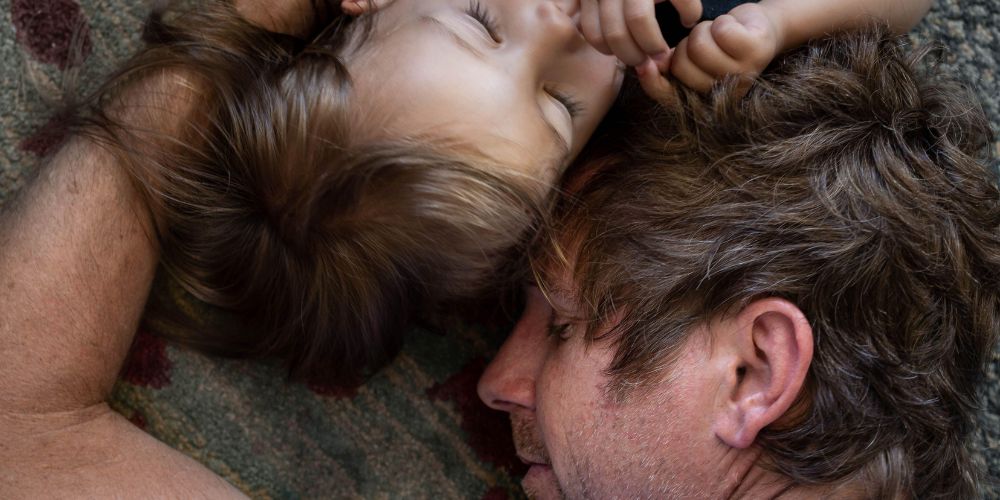 Dad sleeping on the floor with his kid.
