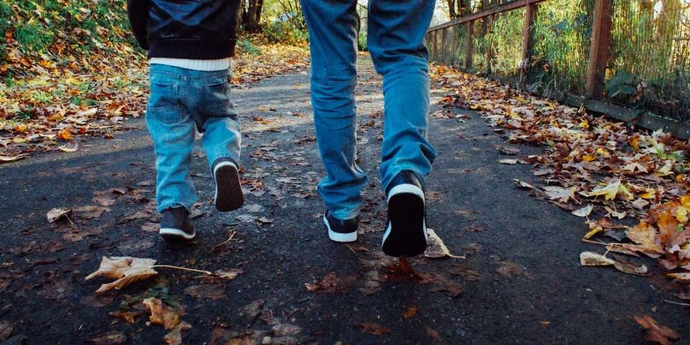 A dad walking along a quiet path with his young son.